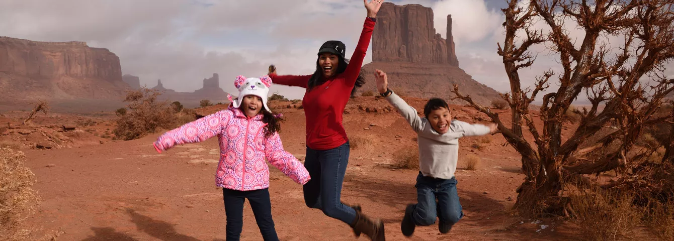 Family in desert jumping in the air happily. 