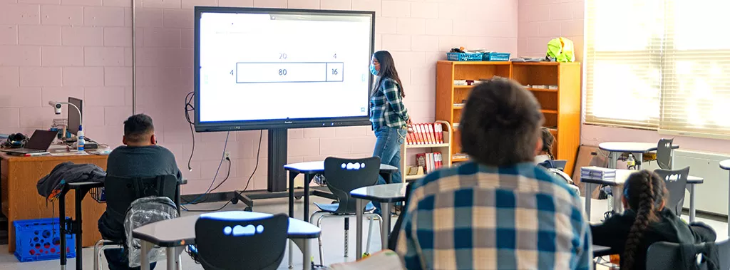 Female teacher at a digital board instructing a class.