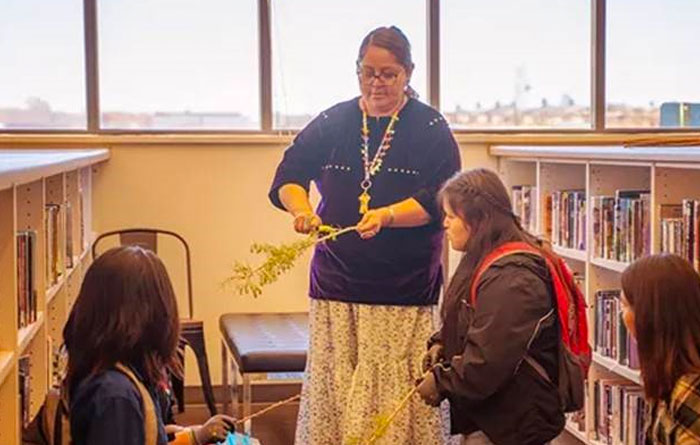 Teacher showing students Native skills in the library.