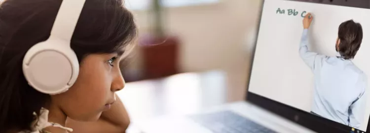 Young girl with white headphones watching a video on a laptop.