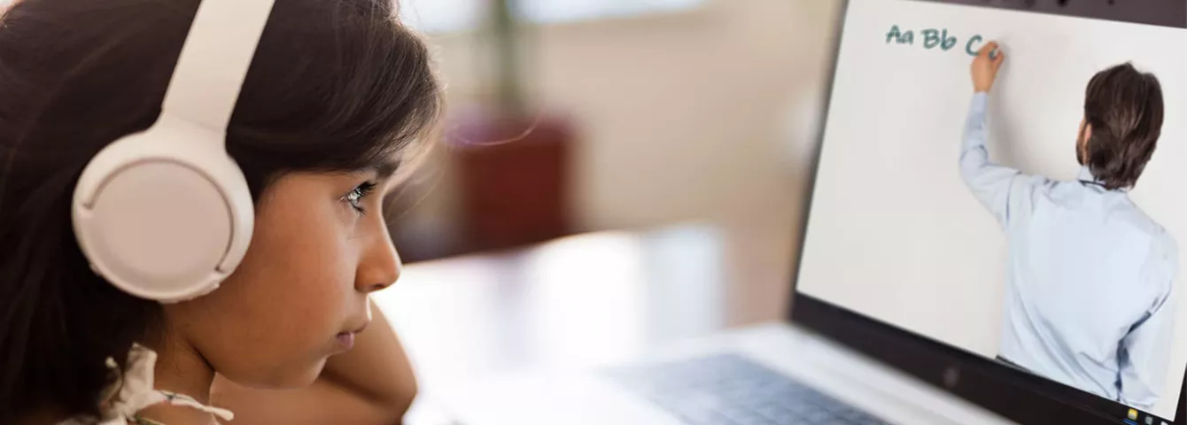 Young girl with white headphones watching a video on a laptop.